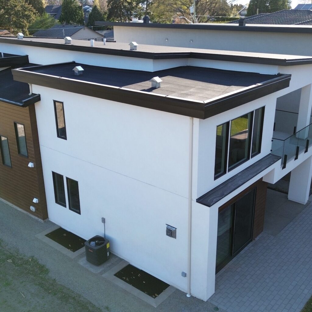 Black custom sheet metal, Kelowna area: parapet caps and roof-edge flashing on a modern white home