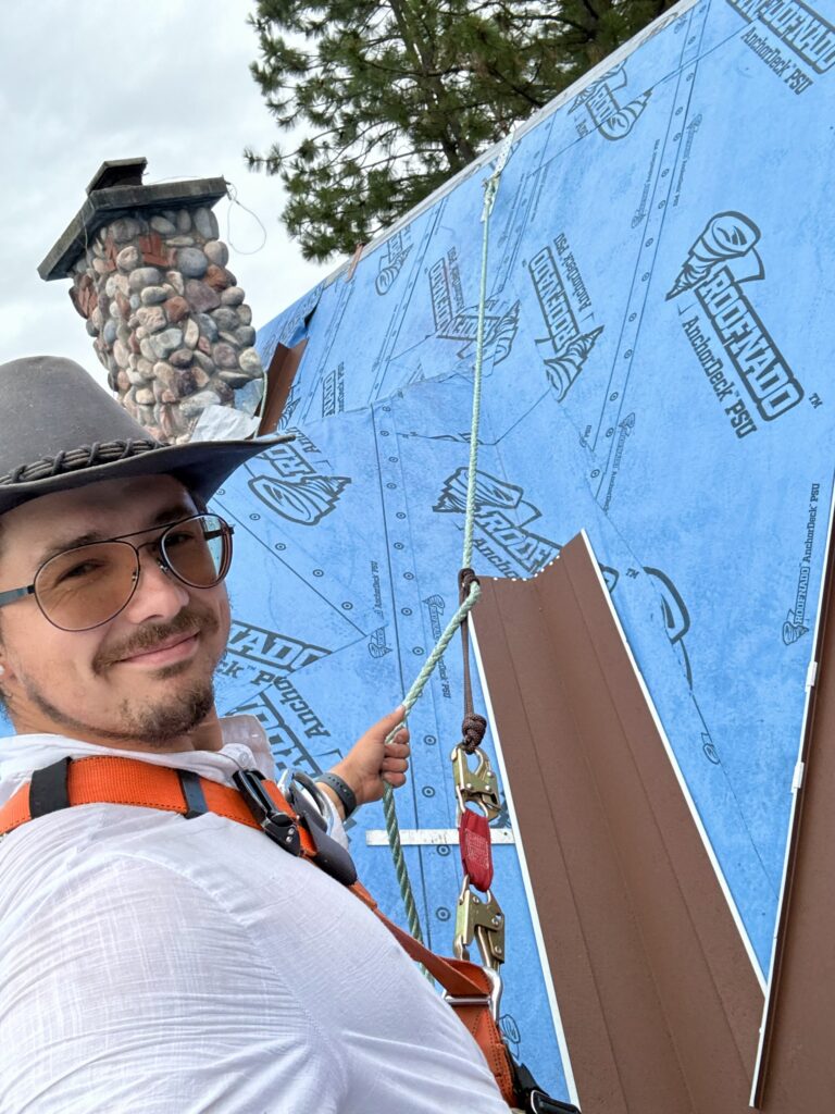 Jared Hanson installing metal flashing over building wrap beside a chimney