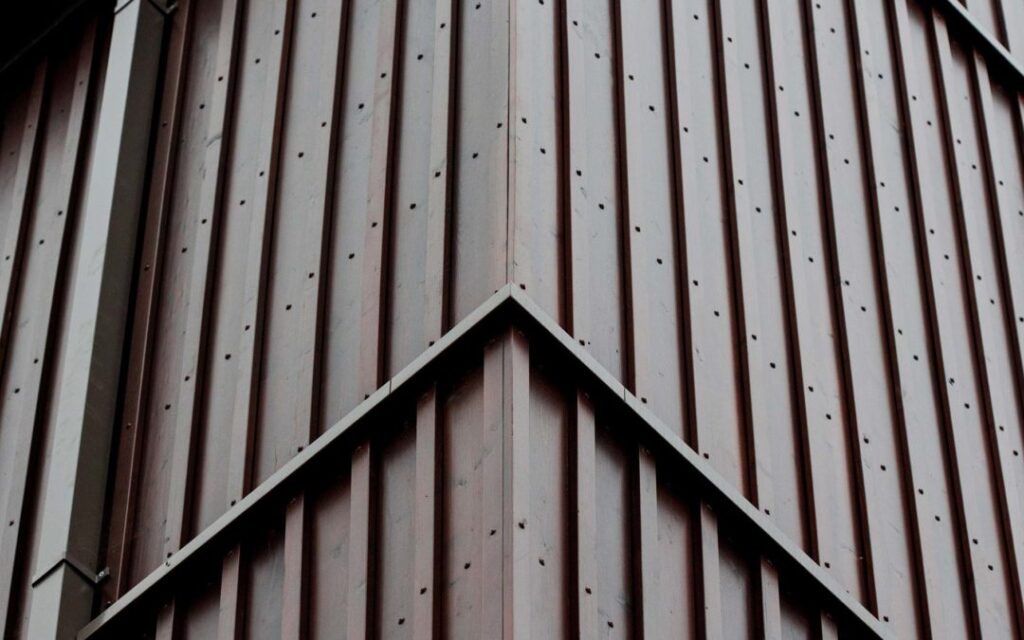 Close-up of a standing seam roof peak in a dark brown painted steel finish